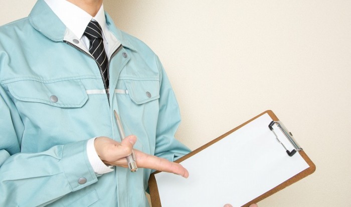 バインダーを持つ作業服の男性